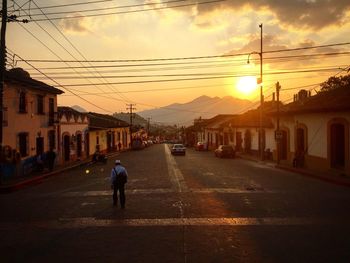 Road passing through city during sunset