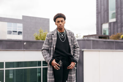 Portrait of young man standing against building