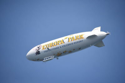 Low angle view of airplane flying against clear blue sky