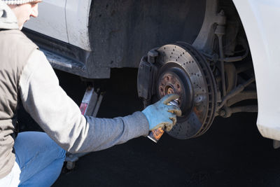 A man lubricates the brake disc in the car, seasonal wheel change