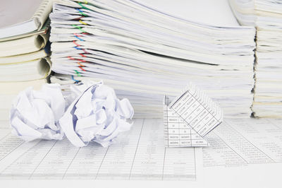 High angle view of crumpled paper balls and model house on financial documents