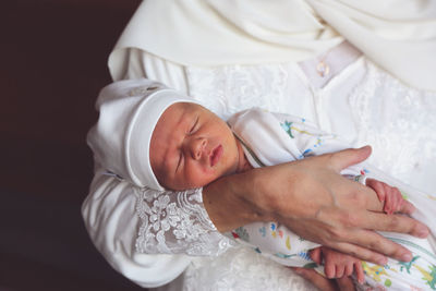 Midsection of woman carrying newborn son