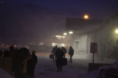 Rear view of people walking on road at night