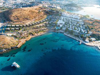 Aerial view of resort villa layout on hill, yacht in the sea lagoon, beach surrounded turquoise sea