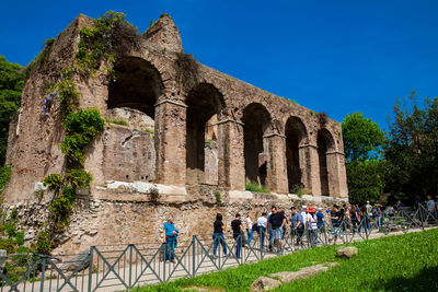 Tourists visiting the ruins of the medieval porch at the roman forum in rome