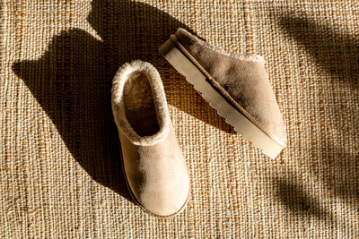 A pair of uggs slippers on a jute rug.