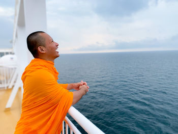 Side view of man looking at sea against sky