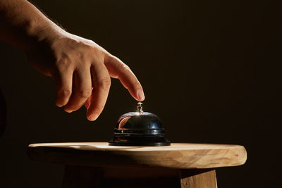 Close-up of hand holding table against black background