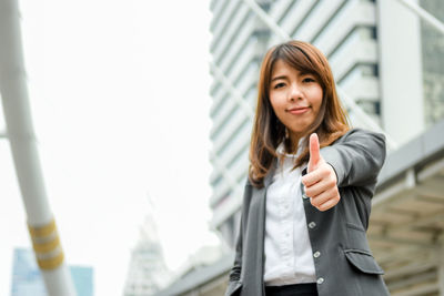 Young businesswoman gesturing while standing in city