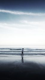 Silhouette person standing on beach against sky