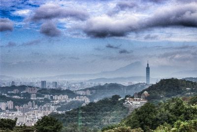 View of cityscape against cloudy sky