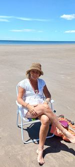 Rear view of woman standing on beach against sky