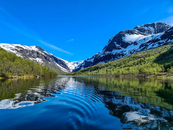 Scenic view of lake and mountains against blue sky