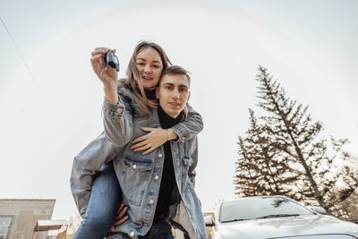 Embracing couple with car keys. young family celebrating buying new car