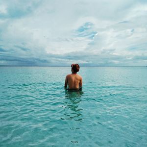 Rear view of shirtless man in sea against sky