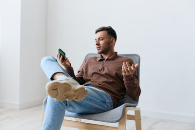 Portrait of young man sitting on sofa at home