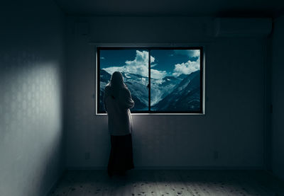 Woman standing by window in snow