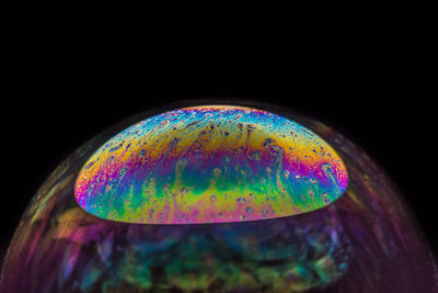 Close-up of multi colored bubbles over black background