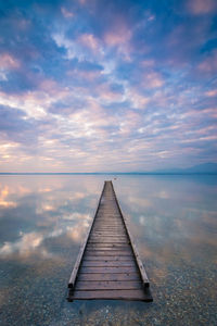 Pier over sea against sky during sunset