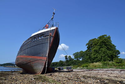 Sailboat moored on beach against clear blue sky