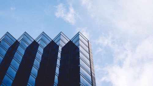 Low angle view of modern building against cloudy sky