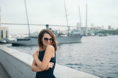 Beautiful brunette girl in a blue dress and sunglasses in the port. 