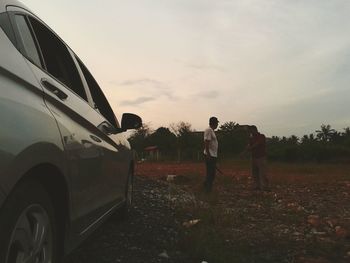 Men standing on road against sky