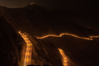 Light trails on road against sky at night