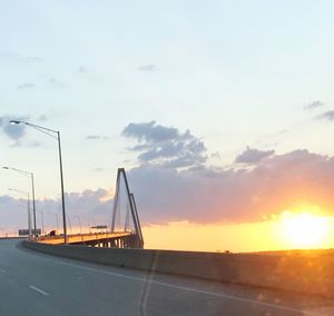 Road by sea against sky during sunset