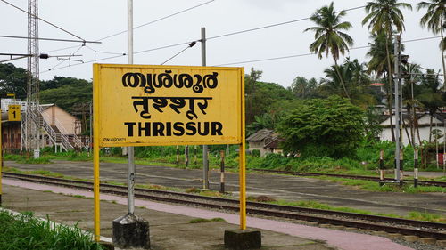 Information sign by trees against sky