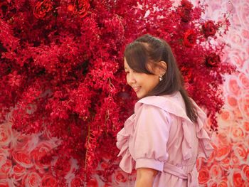 Side view of young woman standing amidst plants