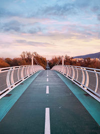 Road leading towards bridge against sky at sunset