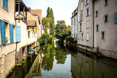 Scenic view of buildings along canal against cloudy sky