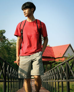 Full length of teenage girl standing on railing against sky