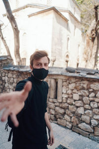 Portrait of young man standing against building in city