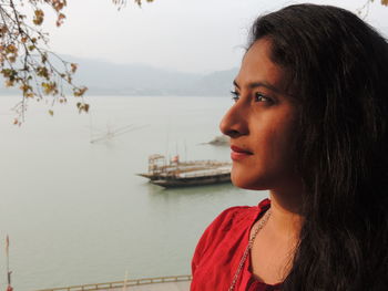 Close-up of thoughtful young woman against lake