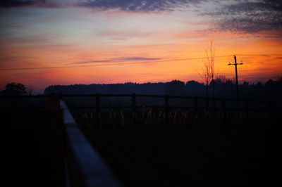 Silhouette fence against sky at sunset