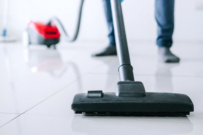 Low section of man cleaning tiled floor at home