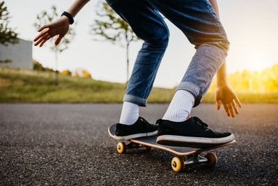 Low section of man skateboarding on road
