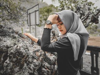 Side view of young woman standing on rock