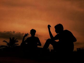 Silhouette people photographing against sky during sunset