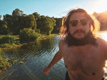 Portrait of shirtless man with sunglasses against sky