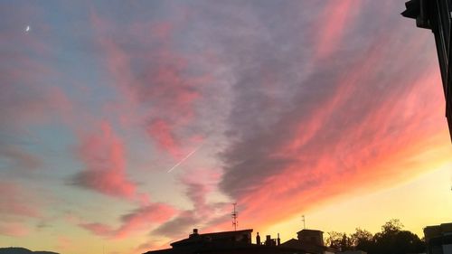 Low angle view of vapor trails in sky at sunset