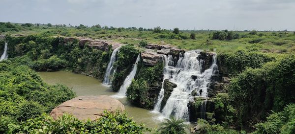 Scenic view of waterfall in forest against sky