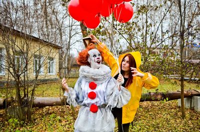 Women standing with balloons against bare trees