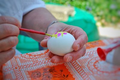 Cropped hand of person painting egg on table