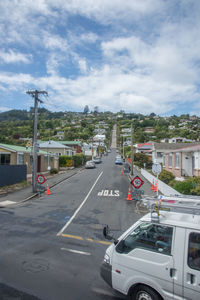 Vehicles on road against cloudy sky