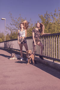 Women tossing hair while standing by dogs on footbridge