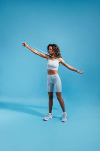 Young woman resistance band against blue background