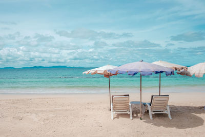 Chair on beach against sky